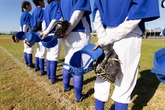 Diverso gruppo di giocatrici di baseball in piedi sul campo con le mani dietro la schiena prima della partita. squadra di baseball femminile, allenamento sportivo, solidarietà e impegno. — Foto stock