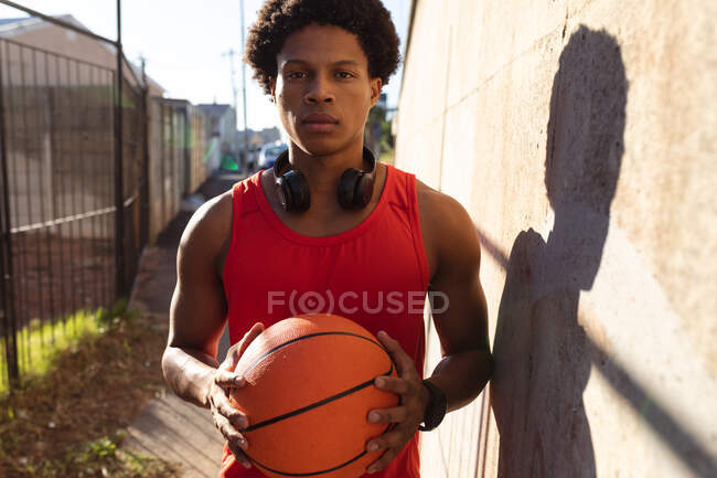 Retrato de homem afro-americano em forma exercitando-se na cidade segurando basquete na rua. fitness e estilo de vida urbano ativo ao ar livre. — Fotografia de Stock