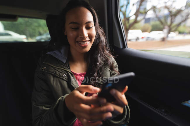 Sorridente donna asiatica seduta in taxi, utilizzando smartphone. indipendente giovane donna in giro per la città. — Foto stock