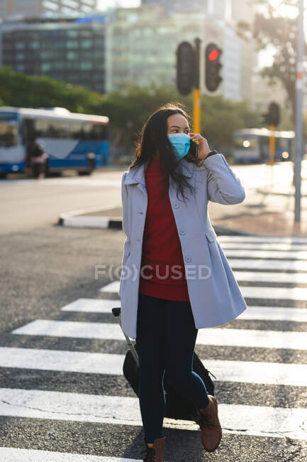 Mulher asiática vestindo máscara facial e cruzando estrada com mala. jovem independente para fora e sobre na cidade durante coronavírus covid 19 pandemia. — Fotografia de Stock