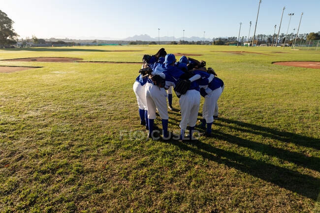 Diverse group of female baseball players standing in huddle on baseball field. female baseball team, sports training and game tactics. — Stock Photo