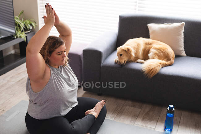 Femme caucasienne pratiquant le yoga, méditant sur le tapis de yoga. mode de vie domestique, passer du temps libre à la maison. — Photo de stock