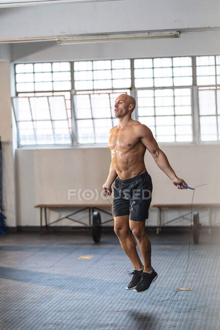 Strong caucasian man exercising at gym, holding rope and skipping. strength and fitness cross training for boxing. — Stock Photo