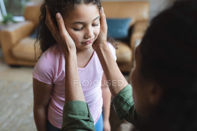 Mixed race mother sitting on sofa and touching her daughter's head. domestic lifestyle and spending quality time at home. — Stock Photo