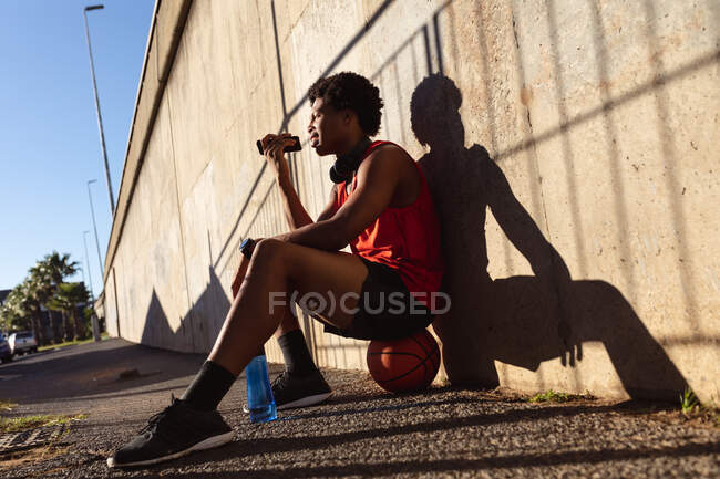 Жирний афроамериканець, який займається спортом у місті, користується смартфоном на вулиці. Фітнес і активне вуличне життя. — стокове фото