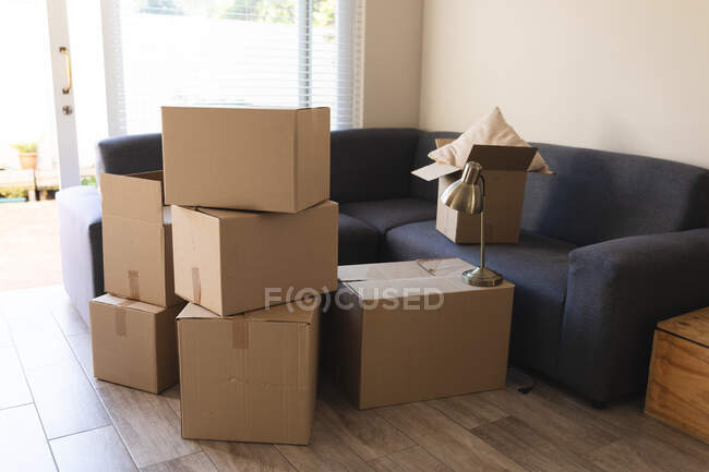 Куча коробок, подготовленных перед переездом дома рядом с диваном. бытовой образ жизни, свободное время дома. — стоковое фото