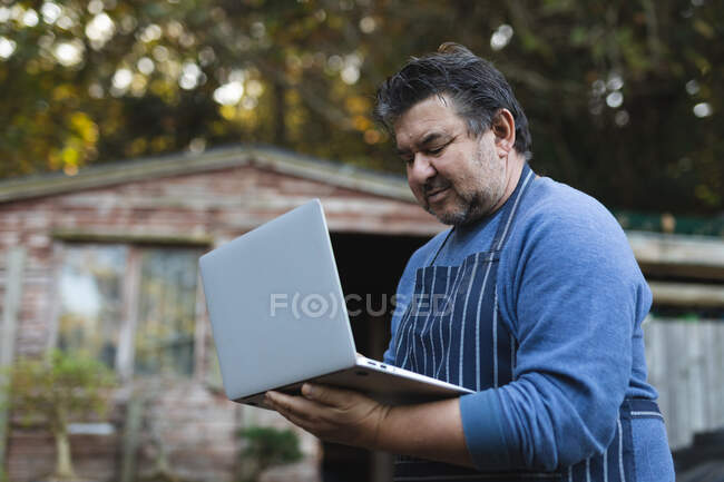Портрет кавказького садівника, який використовує ноутбук у садовому центрі. спеціаліст, що працює в розпліднику бонсайських рослин, незалежний садівничий бізнес . — стокове фото