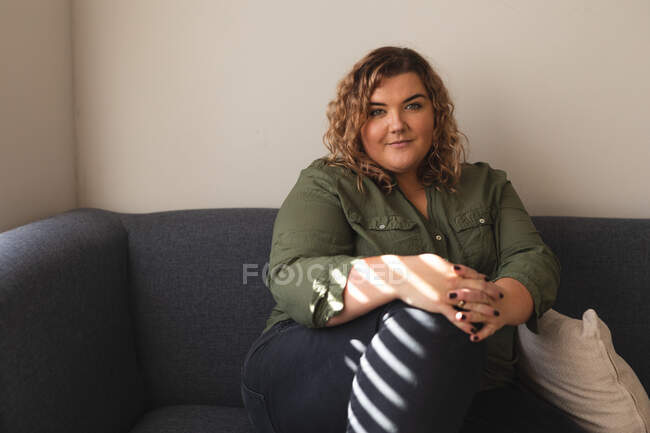 Portrait of caucasian woman smiling and sitting on couch. domestic lifestyle, spending free time at home. — Stock Photo