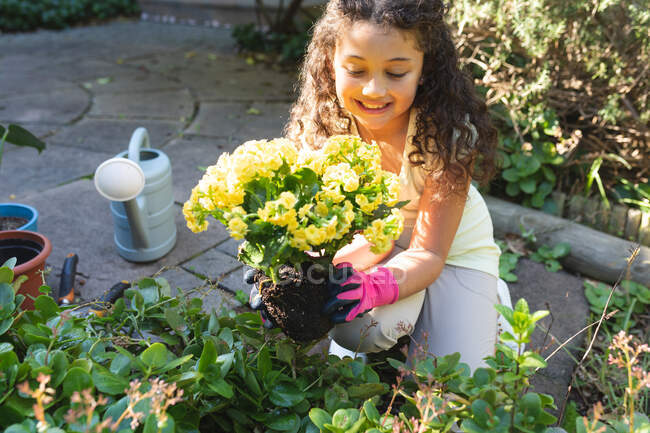 Lächelndes Mischlingsmädchen, das im Hinterhof Blumen pflanzt. Lebensstil und hochwertige Zeit zu Hause verbringen. — Stockfoto