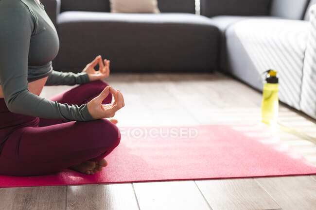 Mujer practicando yoga, meditando en esterilla de yoga. estilo de vida doméstico, pasar tiempo libre en casa. - foto de stock