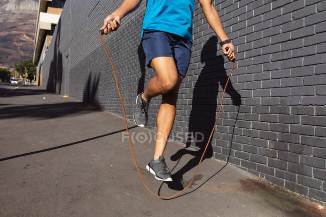 Вмістити чоловіка тренуватися в місті стрибаючи з пропускаючим мотузкою на вулиці. фітнес і активний міський зовнішній спосіб життя . — стокове фото