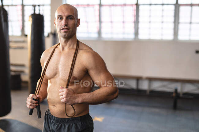 Сильный кавказский мужчина тренируется в спортзале, держит скакалку. силовые и фитнес-кросс тренировки для бокса. — стоковое фото