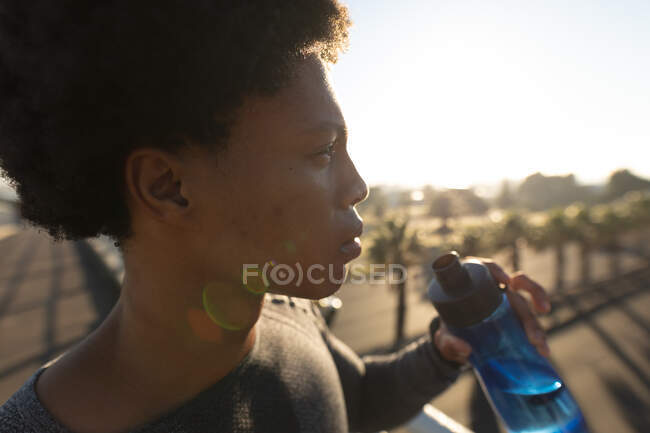 Fit african american man exercising in city resting and drinking water. fitness and active urban outdoor lifestyle. — Stock Photo