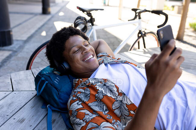 Afroamerikanischer Mann in der Stadt lügt und nutzt Smartphone. digitaler Nomade unterwegs, unterwegs in der Stadt. — Stockfoto