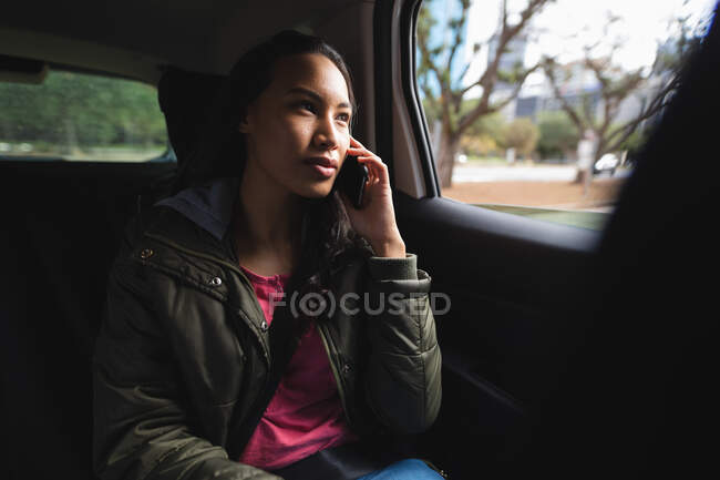 Asian woman sitting in taxi, talking on smartphone. independent young woman out and about in the city. — Stock Photo