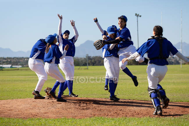 Diverse group of happy female baseball players celebrating on sunny baseball field after game. female baseball team, sports training, togetherness and commitment. — Stock Photo