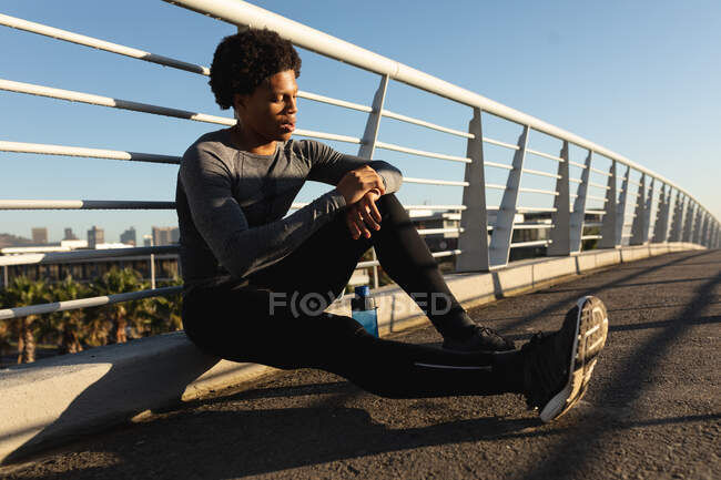 Uomo afro-americano in forma che si esercita in città riposando in strada. fitness e stile di vita urbano attivo all'aperto. — Foto stock