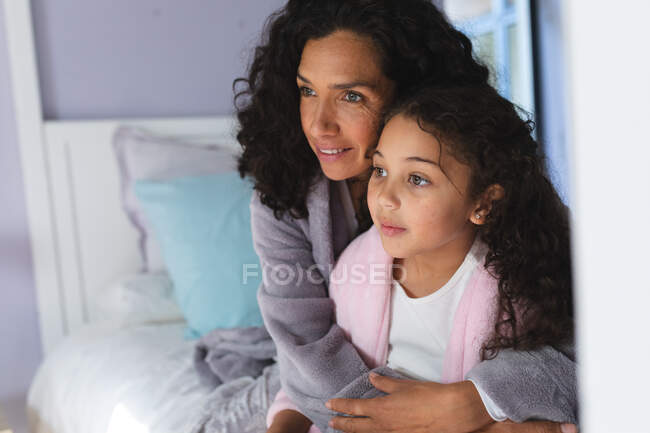 Glückliche gemischte Rasse Mutter und Tochter sitzen auf dem Bett und umarmen sich. Lebensstil und hochwertige Zeit zu Hause verbringen. — Stockfoto