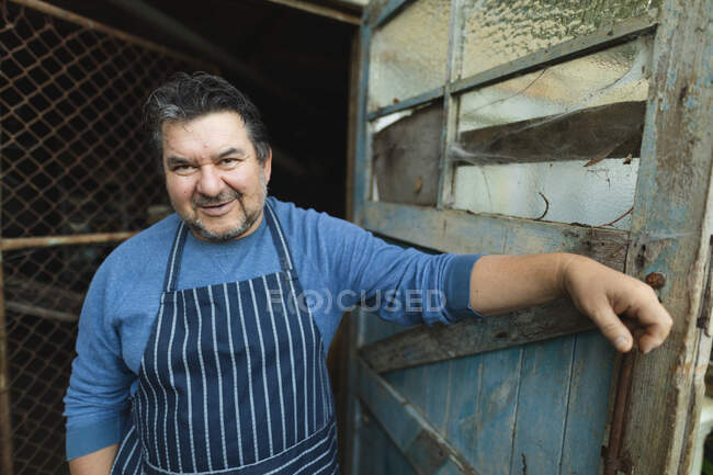Портрет улыбающегося кавказского садовника, смотрящего в камеру в центре сада. специалист, работающий в питомнике бонсай, независимый садоводческий бизнес. — стоковое фото