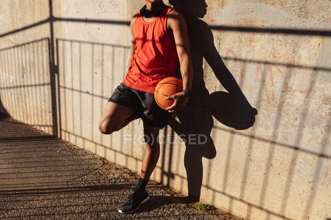 Fit african american man exercising in city holding basketball in the street. fitness and active urban outdoor lifestyle. — Stock Photo