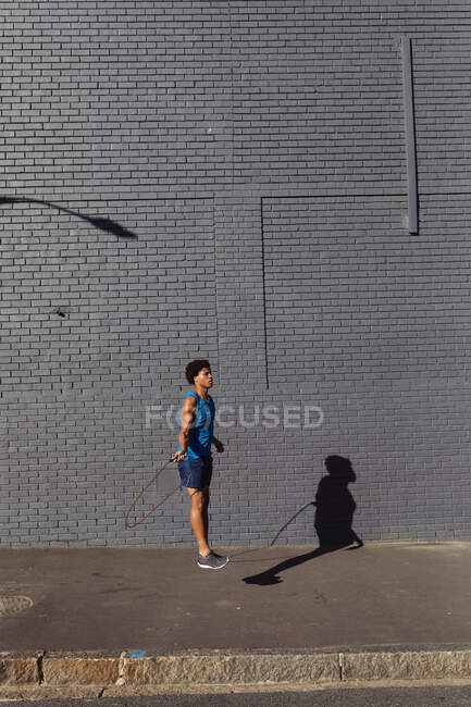 Ajustez l'homme afro-américain faisant de l'exercice en ville en sautant avec une corde à sauter dans la rue. forme physique et mode de vie urbain actif. — Photo de stock