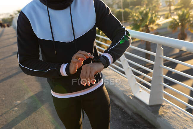 Uomo in forma che si allena in città controllando smartwatch in strada. fitness e stile di vita urbano attivo all'aperto. — Foto stock