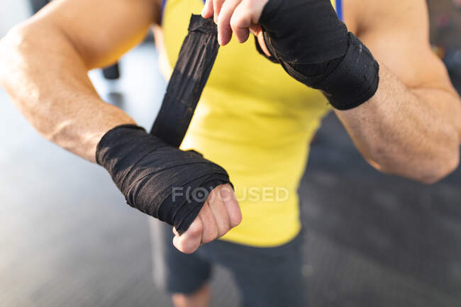 Homem forte exercitando-se no ginásio, envolvendo mãos com fita adesiva. treinamento cruzado de força e aptidão para boxe. — Fotografia de Stock