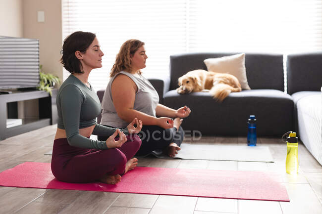 Лесбійська пара практикує йогу, роздумуючи про йогу мат. Домашнє життя, вільний час удома. — стокове фото