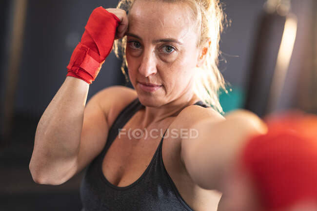 Ritratto di donna caucasica che si allena in palestra, guardando camera boxe. training incrociato di forza e fitness per la boxe. — Foto stock