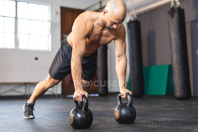 Homme caucasien faisant de l'exercice au gymnase, faire des pompes en utilisant des poids. musculation et fitness cross training pour la boxe. — Photo de stock