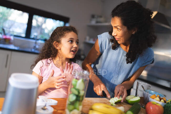 Feliz madre mestiza e hija cocinando juntas en la cocina. estilo de vida doméstico y pasar tiempo de calidad en casa. - foto de stock