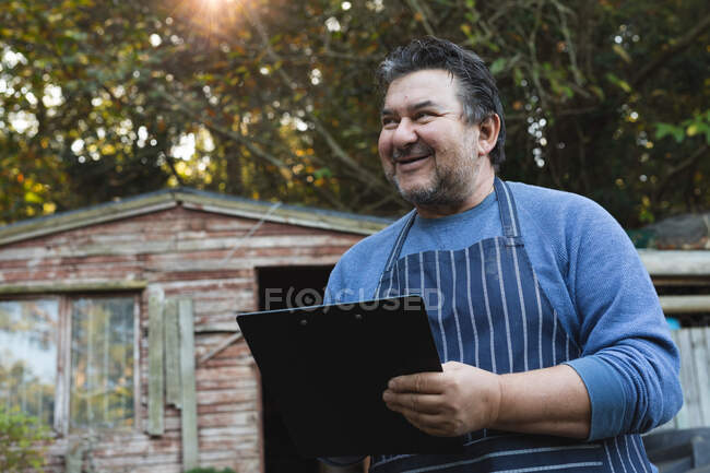 Portrait of smiling caucasian male gardener using tablet at garden centre. specialist working at bonsai plant nursery, independent horticulture business. — Stock Photo