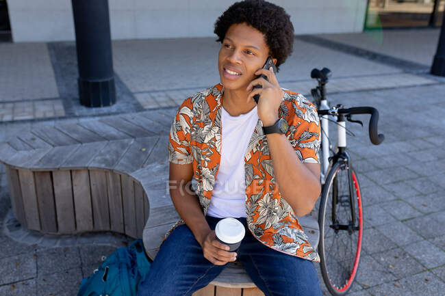 Afrikanischer Mann in der Stadt sitzt und nutzt Smartphone. digitaler Nomade unterwegs, unterwegs in der Stadt. — Stockfoto