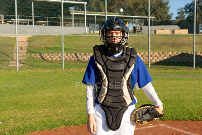 Porträt einer kaukasischen Baseballspielerin, die mit Fangschutz und Helm auf dem Feld steht. Baseballspielerinnen, vorbereitet und auf das Spiel wartend. — Stockfoto