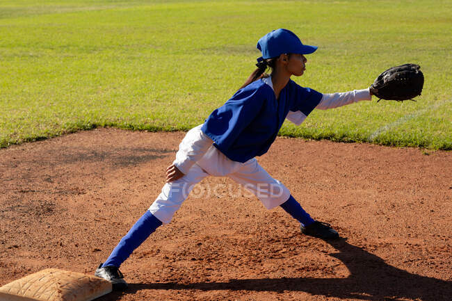Jogadora de beisebol mista corrida em pé no campo de beisebol ensolarado atingindo para pegar bola. time de beisebol feminino, treinamento esportivo e táticas de jogo. — Fotografia de Stock