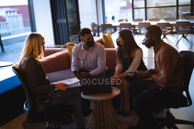 Diverse group of business colleagues wearing face masks and having meeting. working in business at a modern office during coronavirus covid 19 pandemic. — Stock Photo