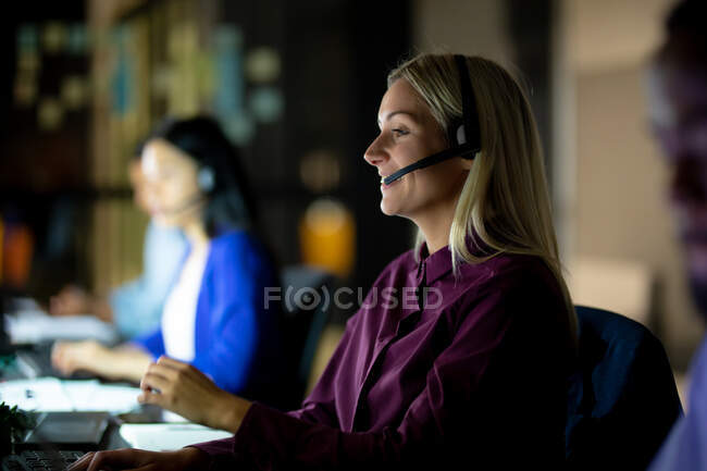 Caucasian businesswoman working at night wearing headset. working late in business at a modern office. — Stock Photo