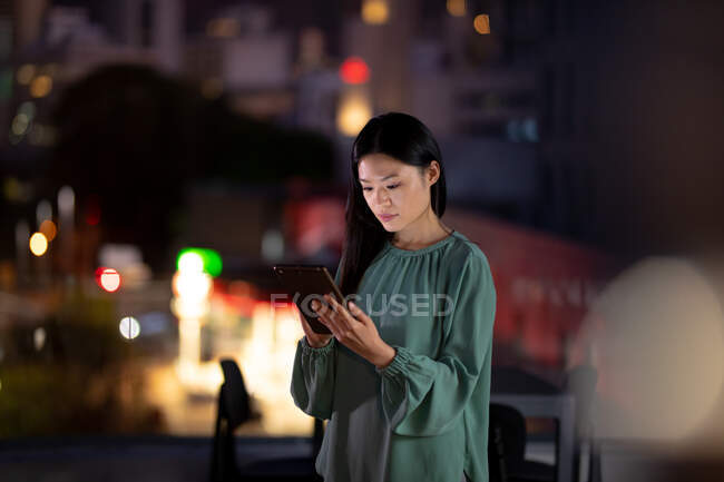 Mujer de negocios asiática que trabaja por la noche usando tableta. trabajar hasta tarde en los negocios en una oficina moderna. - foto de stock