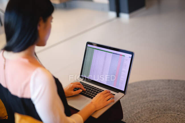 Mujer de negocios asiática sentada en el sofá y trabajando en el portátil. trabajar en un negocio en una oficina moderna. - foto de stock