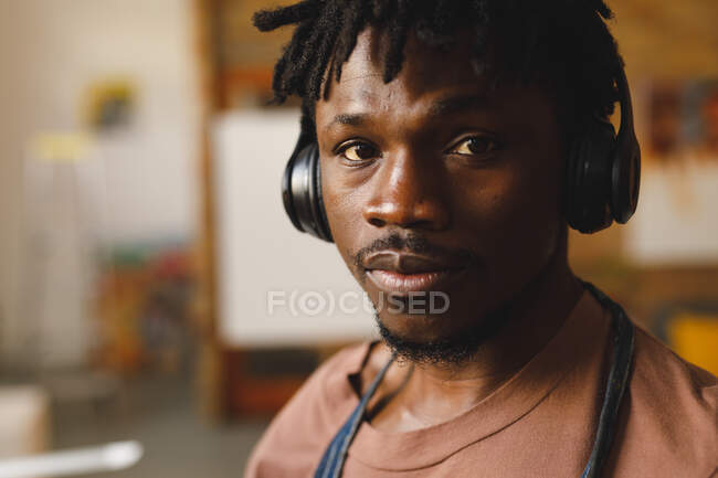 Retrato de pintor americano africano no trabalho usando fones de ouvido no estúdio de arte. criação e inspiração em um estúdio de pintura de artistas. — Fotografia de Stock