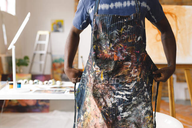 Pittore afroamericano di sesso maschile al lavoro indossando grembiule in studio d'arte. creazione e ispirazione in uno studio di pittura artisti. — Foto stock