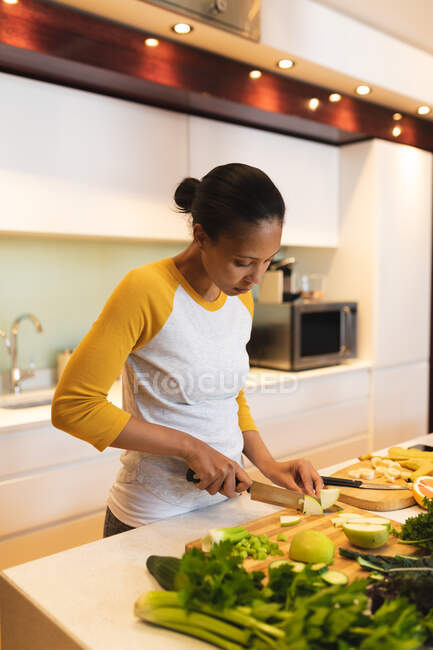 Donna razza mista in piedi in cucina tagliare verdure. stile di vita domestico, godendo del tempo libero a casa. — Foto stock