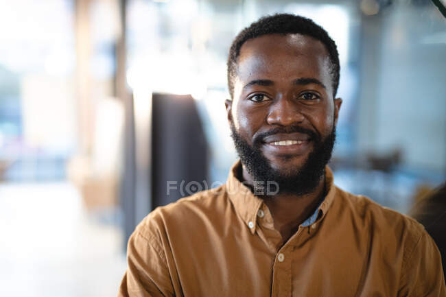 Porträt eines lächelnden afrikanisch-amerikanischen Geschäftsmannes, der in die Kamera blickt. Arbeit in einem modernen Büro. — Stockfoto