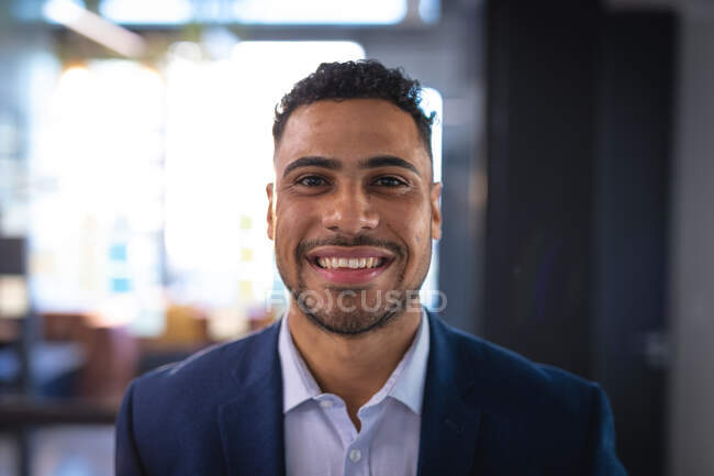 Retrato de sonriente hombre de negocios de raza mixta mirando a la cámara. trabajar en un negocio en una oficina moderna. - foto de stock
