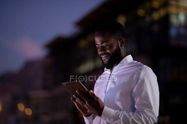 Африканський американський бізнесмен, який працює вночі, користується смартфоном. Працював у сфері бізнесу в сучасному офісі.. — стокове фото
