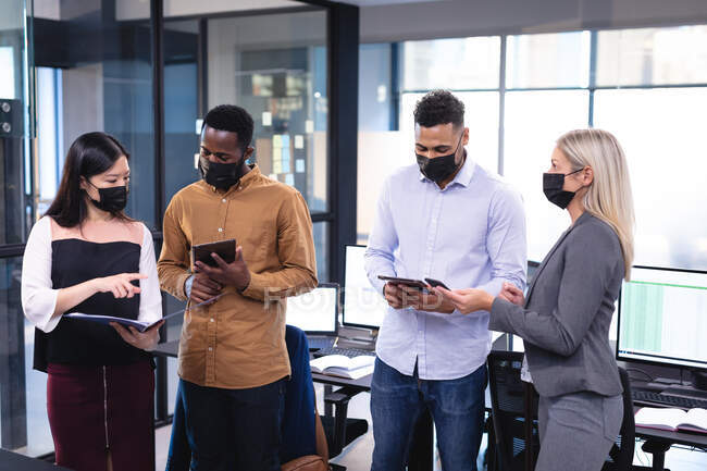 Diverse group of business colleagues wearing face masks and having meeting. working in business at a modern office during coronavirus covid 19 pandemic. — Stock Photo