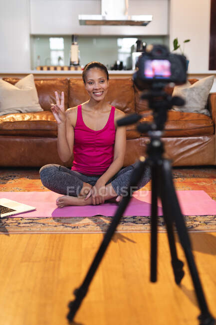 Lächelnde Mischlingshündin im Wohnzimmer, die Yoga-Vlog mit Laptop und Kamera macht. häuslicher Lebensstil, Freizeit zu Hause genießen. — Stockfoto
