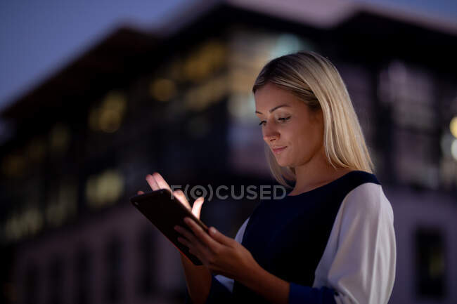 Mulher de negócios caucasiana trabalhando à noite usando smartphone. trabalhando até tarde em negócios em um escritório moderno. — Fotografia de Stock