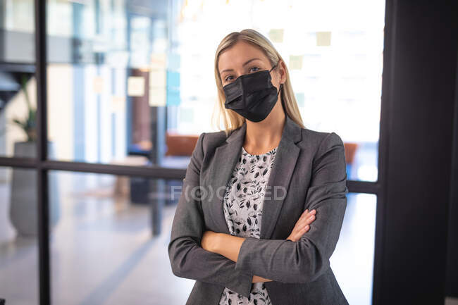 Portrait of caucasian businesswoman wearing face mask and looking at camera. working in business at a modern office during coronavirus covid 19 pandemic. — Stock Photo