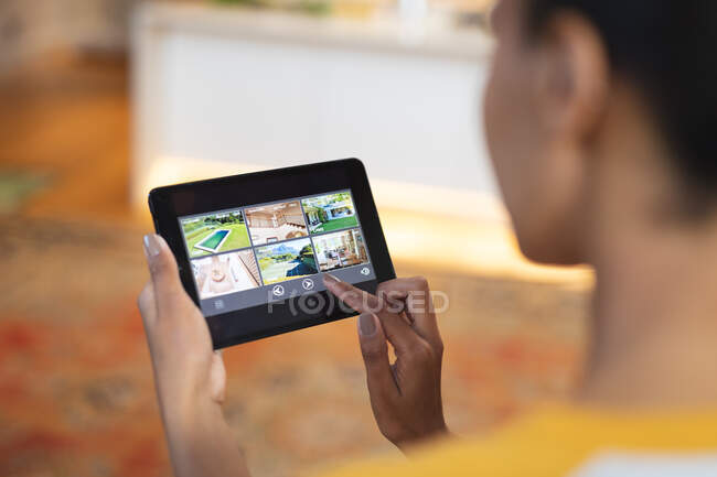 Mixed race woman in kitchen using tablet computer. domestic lifestyle, enjoying leisure time at home. — Stock Photo